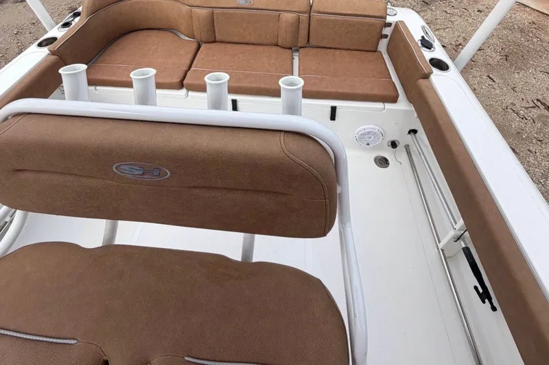 Slide: The Image of 2023 Sea Hunt Ultra 229 boat interior with brown cushioned seating and rod holders. - 4