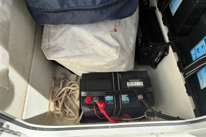 Slide: The Image of Storage compartment of 2023 Sea Hunt Ultra 229 with battery and rope. - 41