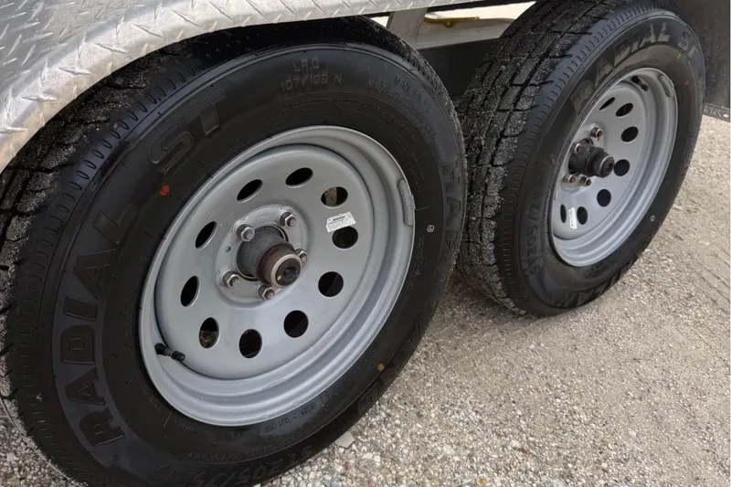 Slide: The Image of Trailer wheels for 2023 Sea Hunt Ultra 229 boat on gravel surface. - 8