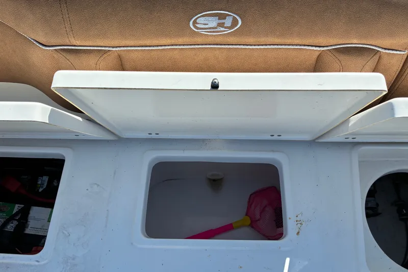 Slide: The Image of 2023 Sea Hunt Ultra 229 boat storage compartment with brown seating and pink net. - 64