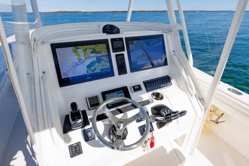 Slide: The Image of The image shows the helm of a 2018 Regulator 34SS boat with two large screens and a steering wheel. - 19