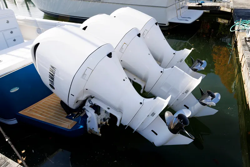 Slide: The Image of Three powerful outboard engines are mounted on the stern of a blue boat docked in the water. - 35