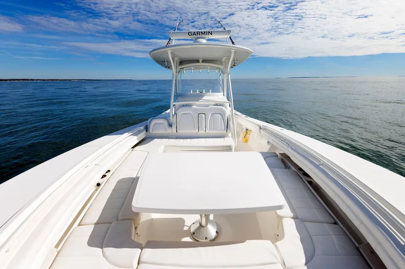 Slide: The Image of A 2018 Regulator 34SS boat on calm water. It features a spacious deck with a table. - 14