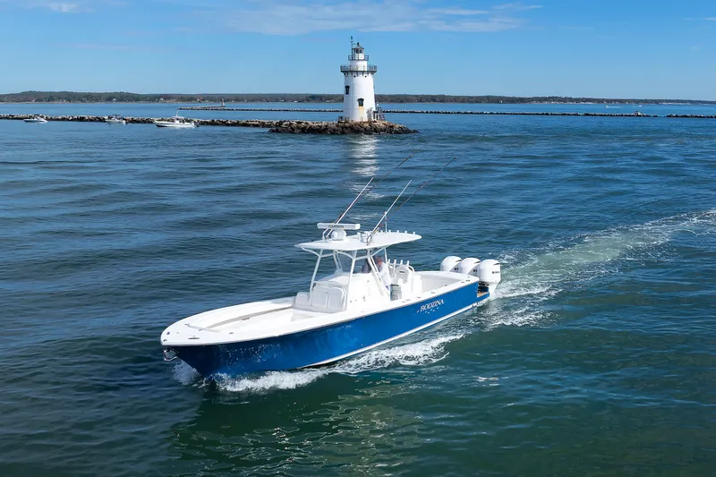 Slide: The Image of A 2018 Regulator 34SS cruising on the water, with a lighthouse in the background. - 2