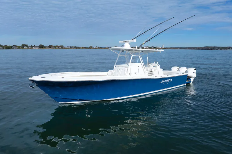 The Image of A blue boat floating on calm water, featuring three outboard engines and an open cabin. - 6