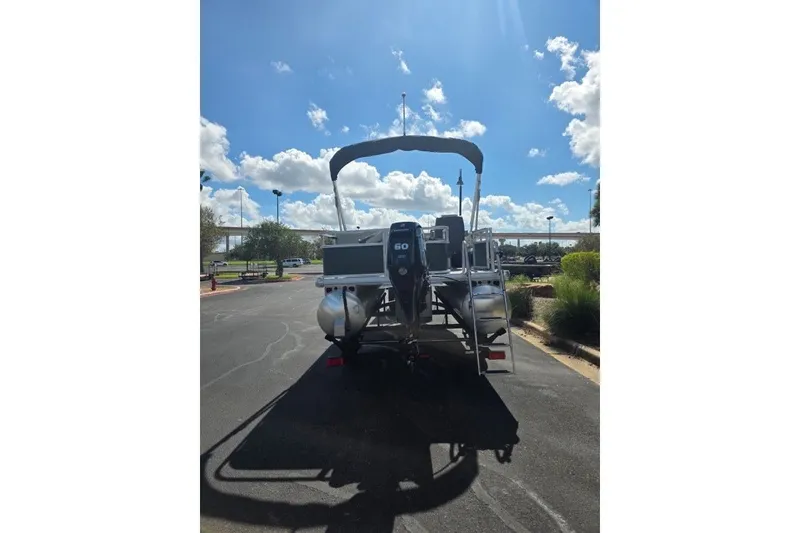 Slide: The Image of 2027 Sun Tracker Bass Buggy 18 DLX pontoon boat parked under a sunny sky. - 14