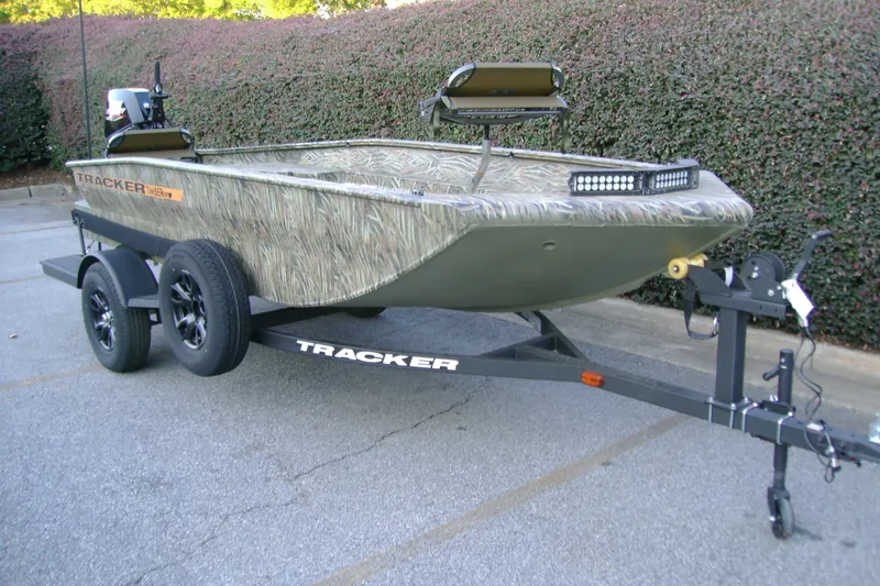 Slide: The Image of 2027 Tracker Grizzly 1553 Timber boat on trailer, camo design, parked outdoors. - 45