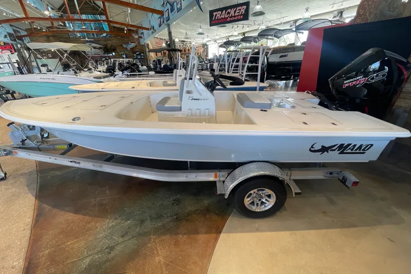 Slide: The Image of 2026 Mako 18 Pro Skiff boat displayed in showroom, featuring sleek design and trailer. - 1