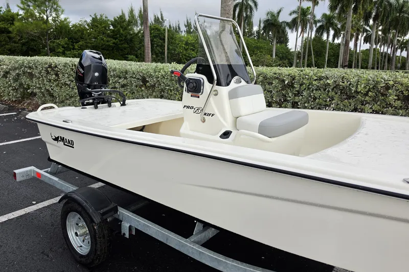 Slide: The Image of 2026 Mako Pro Skiff 13 CC boat on trailer, parked near lush greenery. - 8