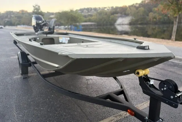 Slide: The Image of 2027 Tracker Grizzly 1654 T Sportsman boat on trailer by a lake. - 13