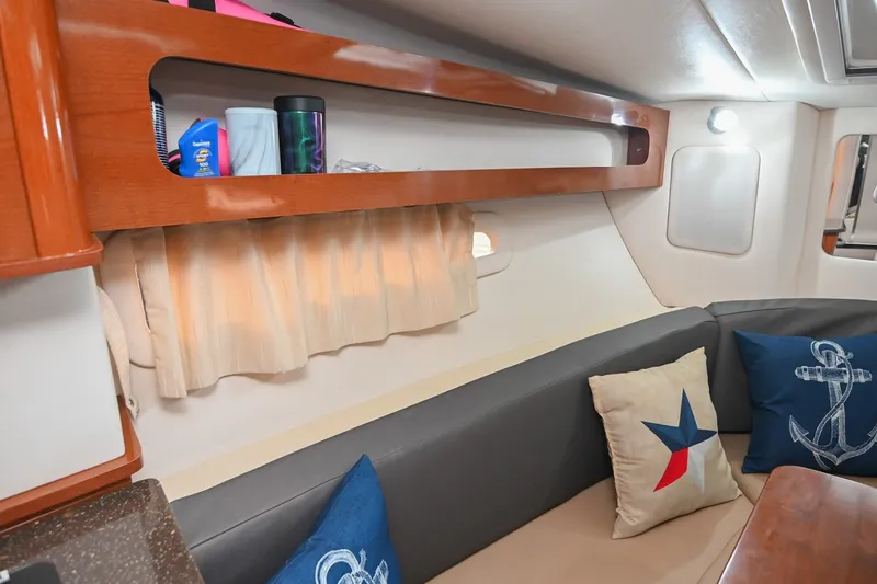 Slide: The Image of Interior of 2014 Sea Ray Sundancer 260 with nautical-themed cushions and wooden shelving. - 51