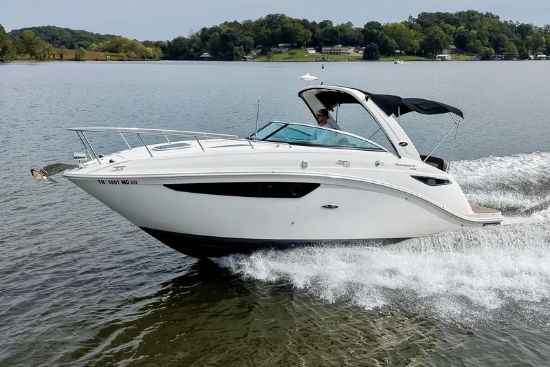 Slide: The Image of 2014 Sea Ray Sundancer 260 cruising on a serene lake with lush green shoreline. - 63