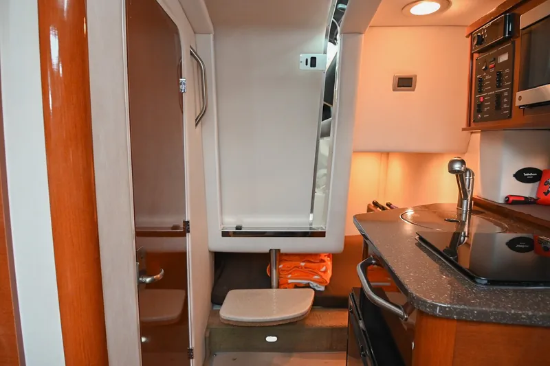 Slide: The Image of Interior of 2014 Sea Ray Sundancer 260, featuring kitchenette and cabin amenities. - 54