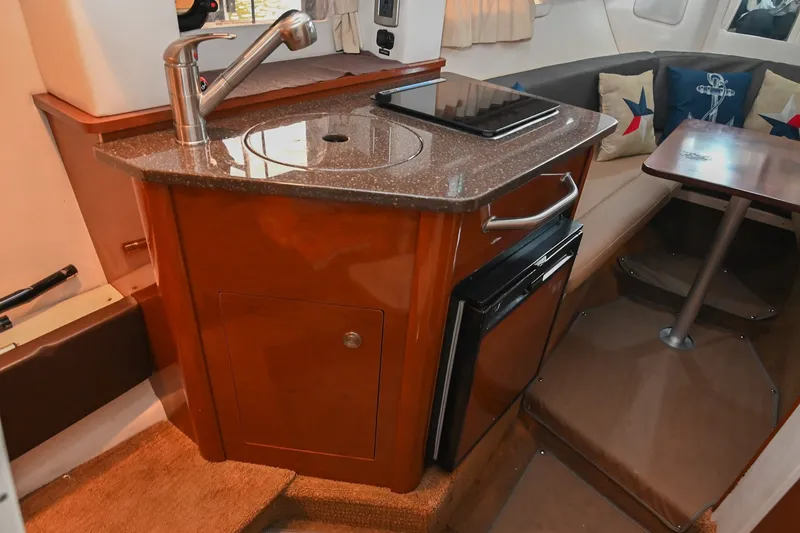 Slide: The Image of Interior of 2014 Sea Ray Sundancer 260, featuring kitchenette and seating area with nautical decor. - 40