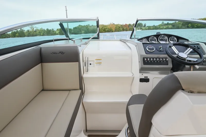 Slide: The Image of 2014 Sea Ray Sundancer 260 boat interior with helm and seating, overlooking a serene lake. - 29