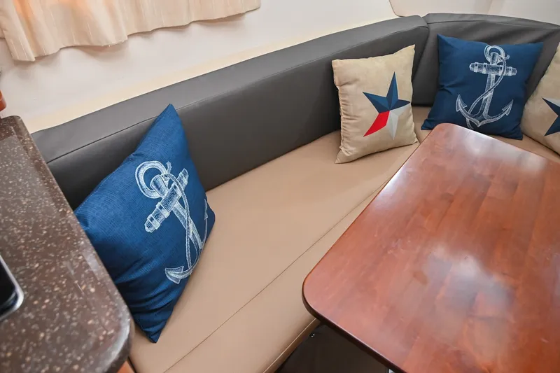 Slide: The Image of Interior of 2014 Sea Ray Sundancer 260 with nautical-themed cushions and wooden table. - 48