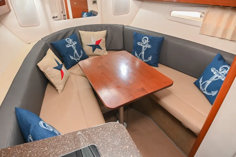 Slide: The Image of Interior of 2014 Sea Ray Sundancer 260 with cozy seating and nautical-themed cushions. - 46