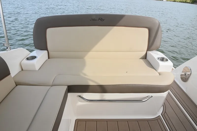 Slide: The Image of 2014 Sea Ray Sundancer 260 boat seating with beige cushions and cup holders by the water. - 25