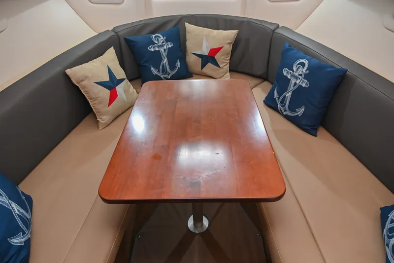 Slide: The Image of Interior of 2014 Sea Ray Sundancer 260 with nautical-themed cushions and wooden table. - 47