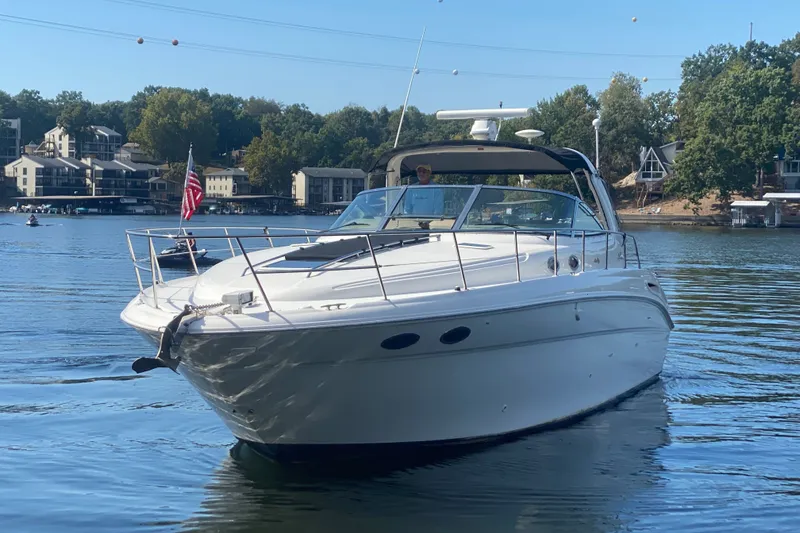 Slide: The Image of 1999 Sea Ray 380 Sundancer yacht cruising on a serene lake with scenic shoreline. - 44