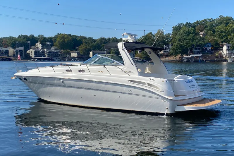 Slide: The Image of 1999 Sea Ray 380 Sundancer yacht on a serene lake with houses in the background. - 4