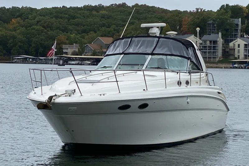 Slide: The Image of 1999 Sea Ray 380 Sundancer yacht on a serene lake with lush green shoreline. - 2