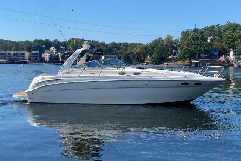 Slide: The Image of 1999 Sea Ray 380 Sundancer yacht on a serene lake with scenic background. - 2