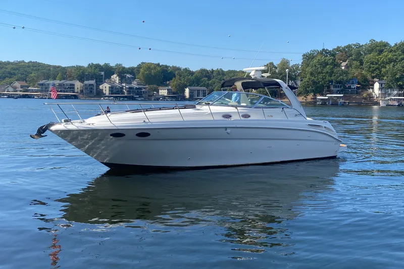Slide: The Image of 1999 Sea Ray 380 Sundancer yacht on a serene lake with scenic background. - 1