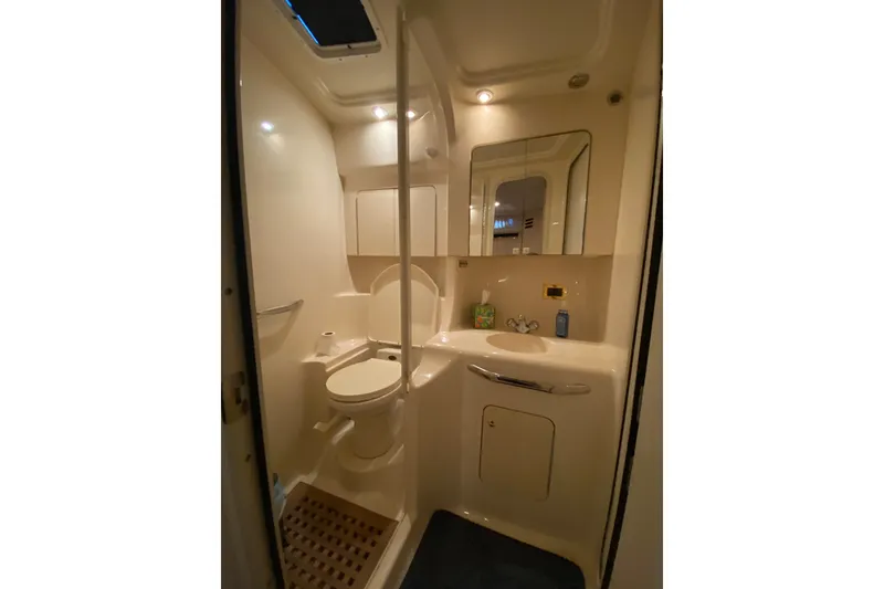 Slide: The Image of 1999 Sea Ray 380 Sundancer bathroom with toilet, sink, and mirror in compact design. - 34
