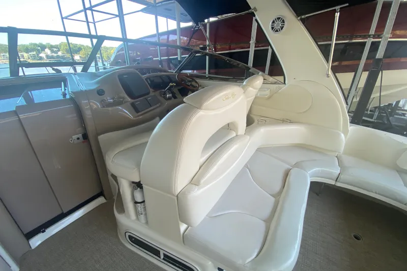 Slide: The Image of 1999 Sea Ray 380 Sundancer cockpit with beige seating and helm, docked by the water. - 22