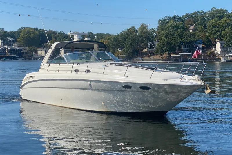 The Image of 1999 Sea Ray 380 Sundancer yacht cruising on a serene lake with scenic background. - 0