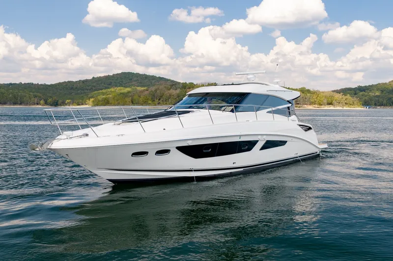 The Image of 2015 Sea Ray 470 Sundancer yacht cruising on a scenic lake under a partly cloudy sky. - 0