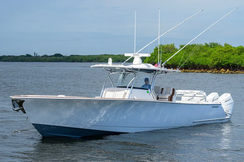 Slide: The Image of 2026 Valhalla V-41 boat cruising on calm waters with lush green shoreline. - 7