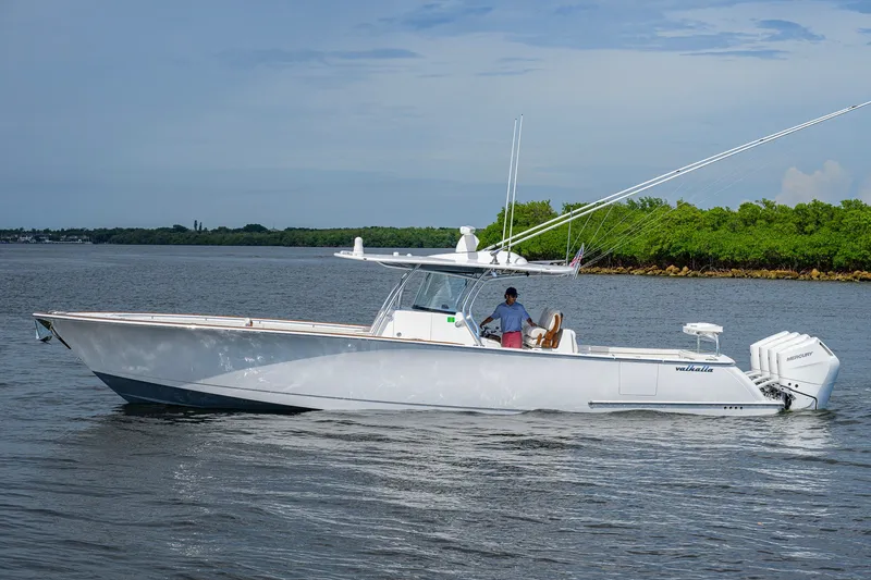 Slide: The Image of 2026 Valhalla V-41 boat cruising on calm waters with lush green shoreline. - 8