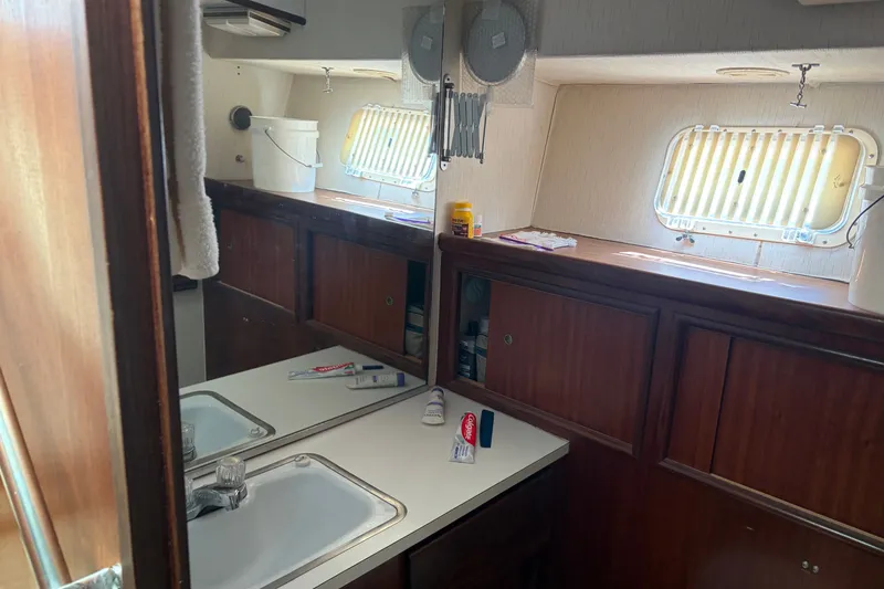 Slide: The Image of 1972 Hatteras 38 Convertible yacht bathroom with sink, mirror, and wooden cabinetry. - 25