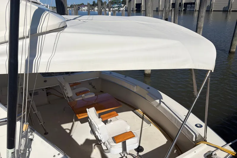 Slide: The Image of 1972 Hatteras 38 Convertible boat with canopy and seating, docked by the water. - 3