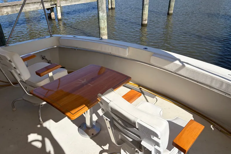Slide: The Image of 1972 Hatteras 38 Convertible boat deck with seating and wooden table by the water. - 5