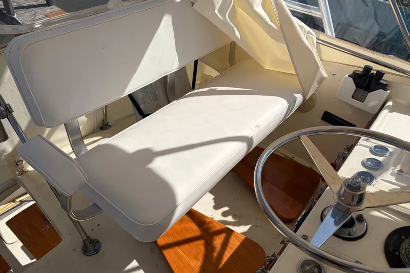 Slide: The Image of Interior of a 1972 Hatteras 38 Convertible boat with white seating and steering wheel. - 16