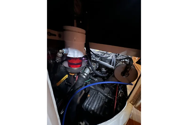 Slide: The Image of Engine compartment of a 1995 Cabo Rico 34 sailboat, showcasing mechanical components and hoses. - 74