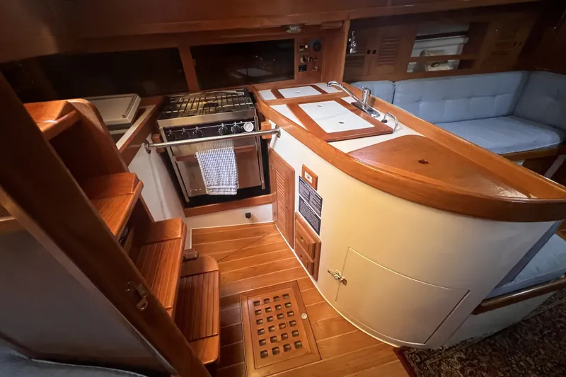 Slide: The Image of Interior of a 1995 Cabo Rico 34 sailboat featuring a compact kitchen and seating area. - 39