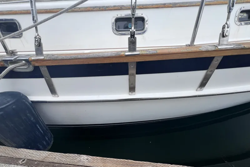 Slide: The Image of Side view of a 1995 Cabo Rico 34 sailboat docked, showing hull and railing details. - 14