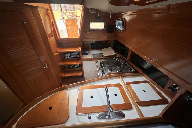 Slide: The Image of Interior of a 1995 Cabo Rico 34 sailboat featuring a wooden galley and storage shelves. - 42