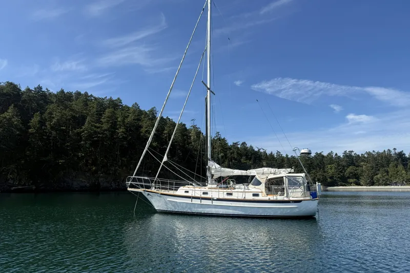 Slide: The Image of Sailboat Cabo Rico 34, 1995 model, anchored in serene waters with forested backdrop. - 1