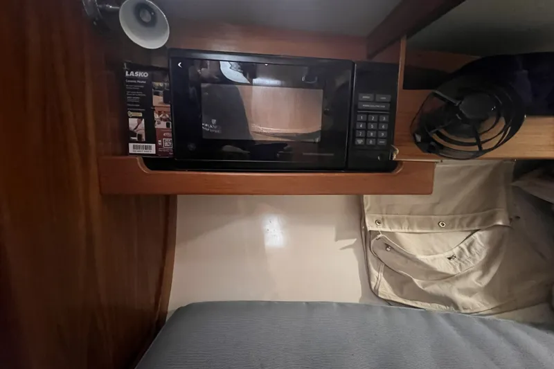 Slide: The Image of Interior of a 1995 Cabo Rico 34 yacht featuring a microwave and storage area. - 51