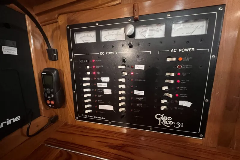 Slide: The Image of Electrical control panel of a 1995 Cabo Rico 34 yacht, featuring DC and AC power switches. - 48