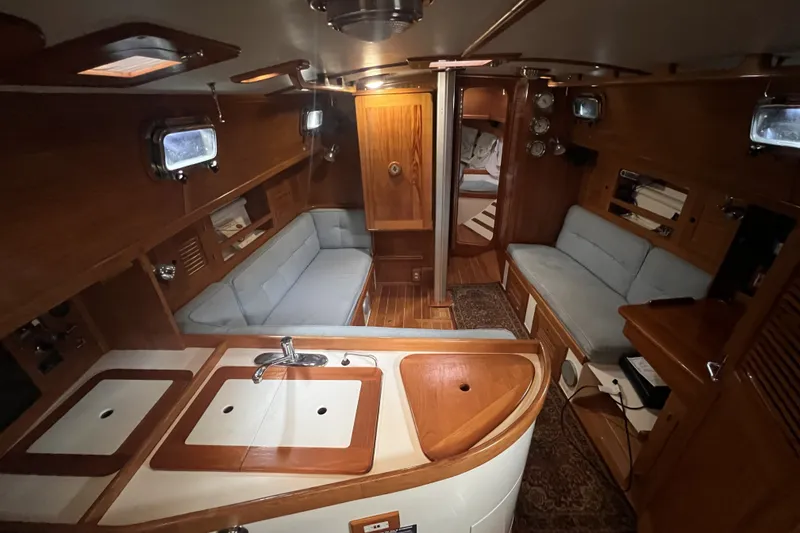 Slide: The Image of Interior of a 1995 Cabo Rico 34 sailboat, featuring wooden cabinetry and cozy seating. - 43