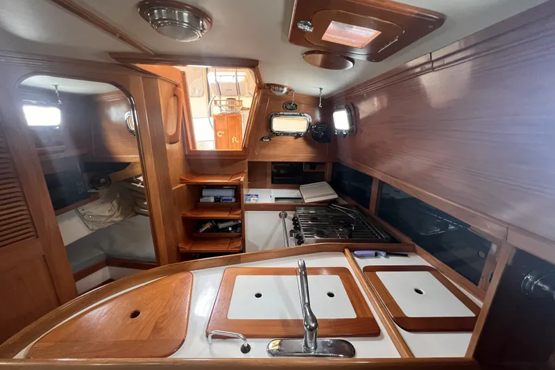 Slide: The Image of Interior of a 1995 Cabo Rico 34 sailboat, featuring a wooden galley and cozy cabin space. - 38