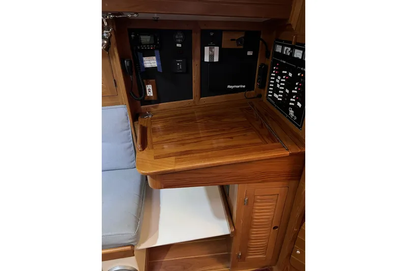 Slide: The Image of Navigation station of a 1995 Cabo Rico 34 sailboat with wooden finish and control panels. - 46