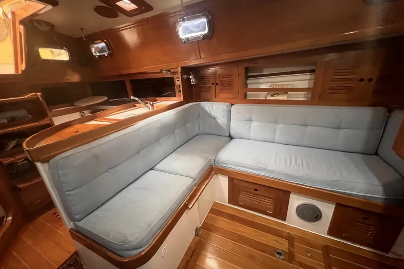 Slide: The Image of Interior of a 1995 Cabo Rico 34 sailboat with wooden finish and blue cushioned seating. - 56