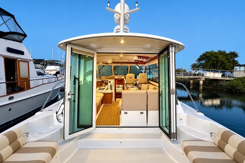 Slide: The Image of 2011 Back Cove 37 yacht interior with open glass doors, showcasing elegant seating and helm. - 11